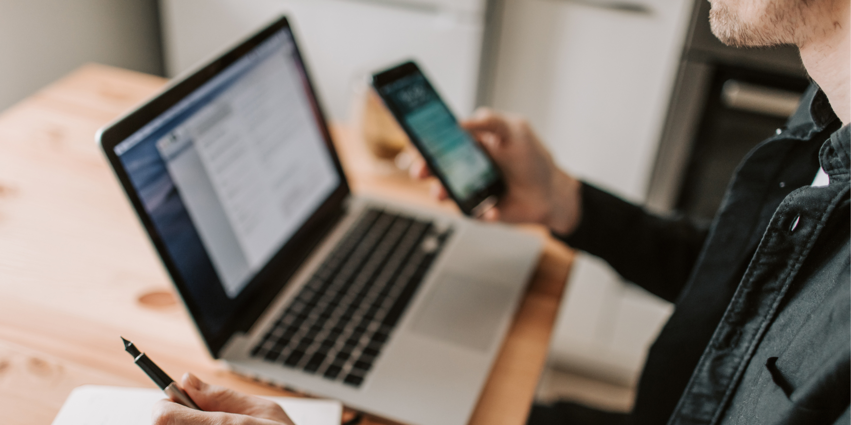 person with an open laptop and a phone in hand