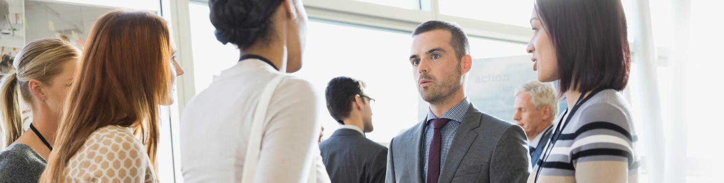 A group of attendees at an event, talking with an event manager.