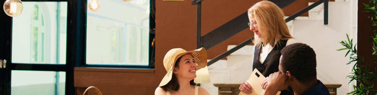 Two hotel guests interacting with a hotel employee, displaying a combination of guest service and guest experience.