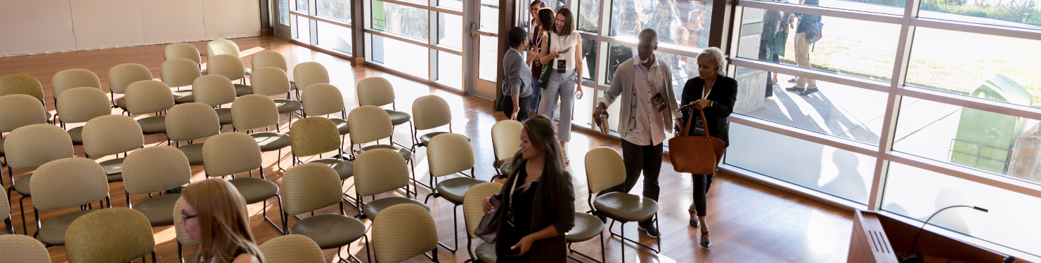 An event venue space, with event attendees walking in to sit down.